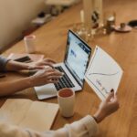 people sitting at the table using a laptop and looking at a piece of paper with a chart