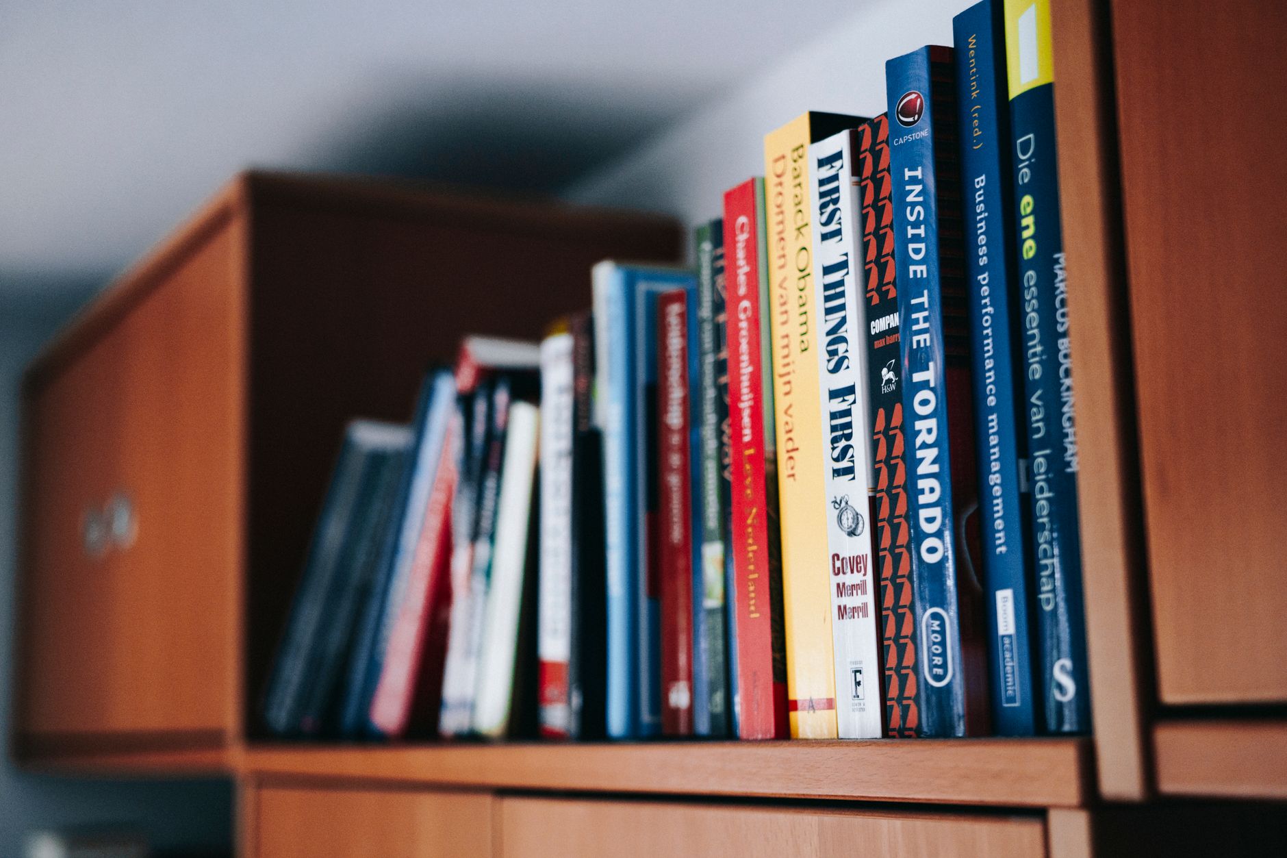 assorted books on brown wooden shelf