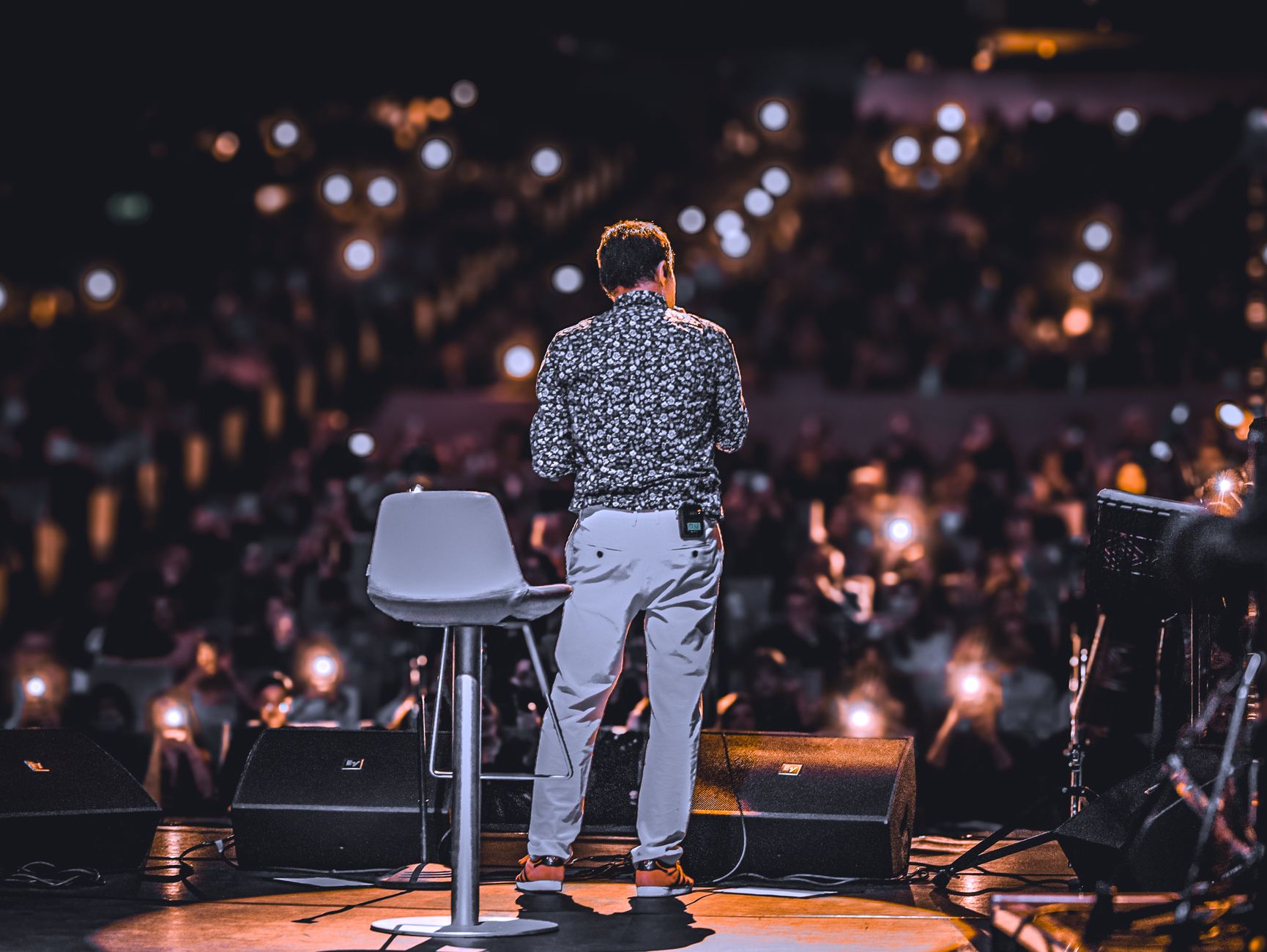 back view of speaker on stage with audience lights