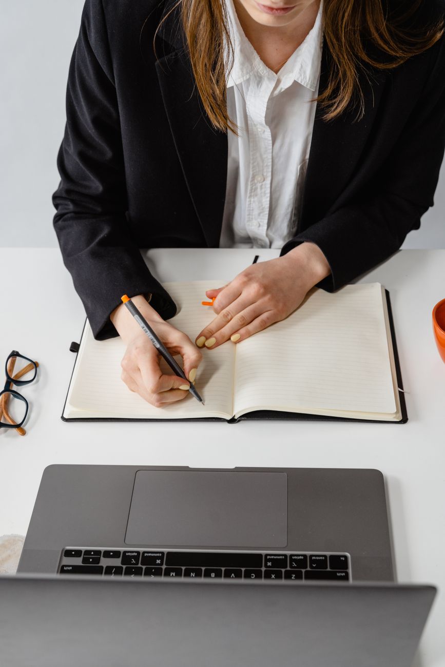 a person in black blazer writing on white paper